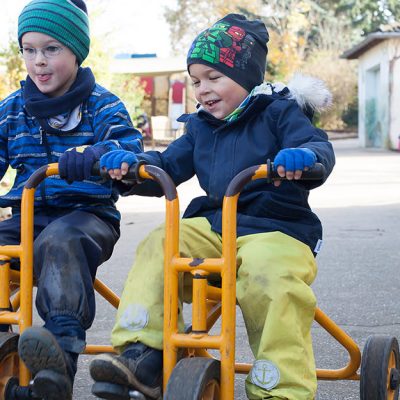 Zwei Jungen fahren im Außenbereich Dreirad