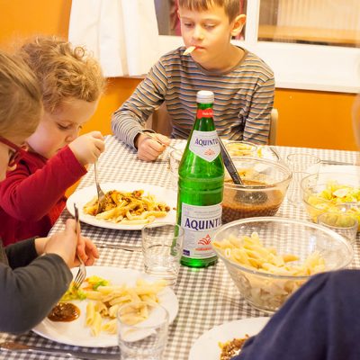 Kinder sitzen am Mittagstisch und essen gemeinsam
